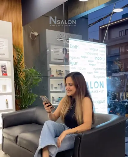 Client in the lounge at N Salon Pitampura, with the L'Oréal Professionnel display behind her